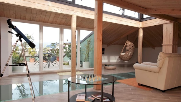 A spacious living area with a telescope, a glass table with books, a sofa, and a hanging chair. - Le Fontanelle B&B (Sarno)