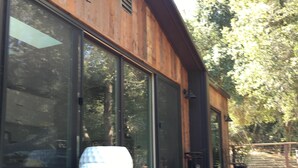 A modern building with large windows, wooden exterior, and a set of outdoor stairs leading to a deck area.