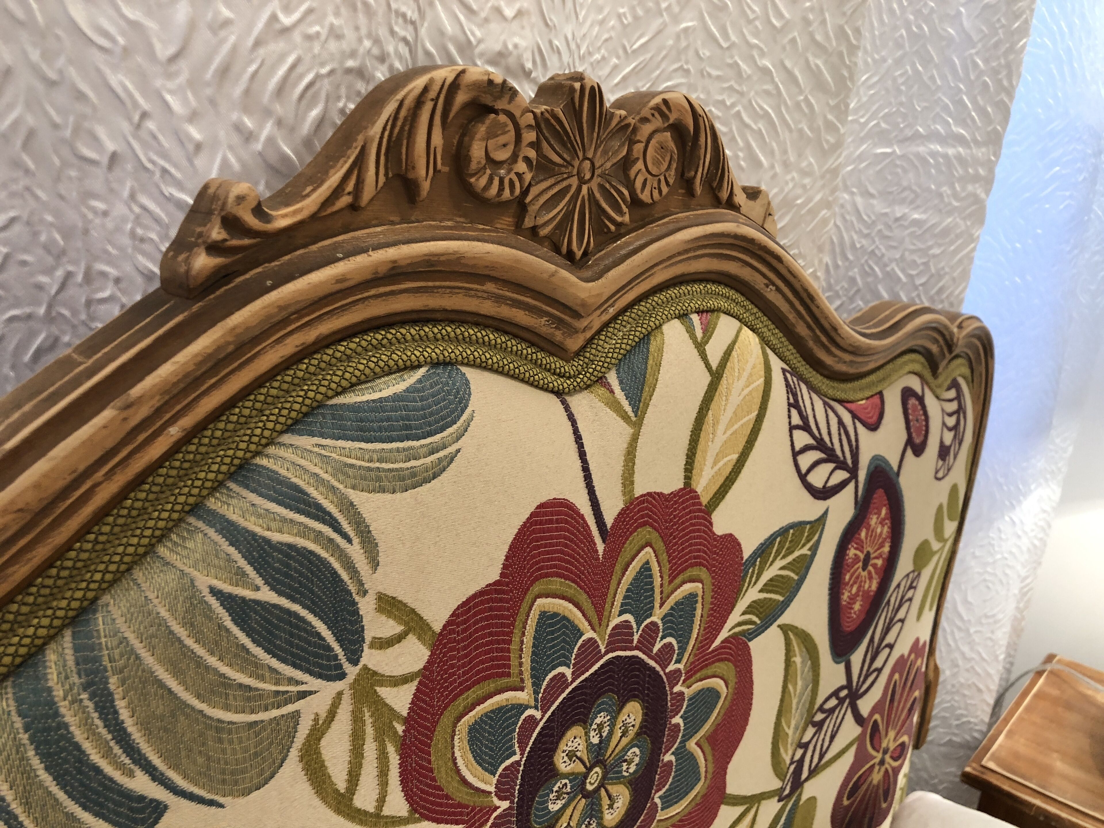 Un gros plan d’une tête de lit ornée d’un motif floral et dotée d’un cadre en bois sculpté.