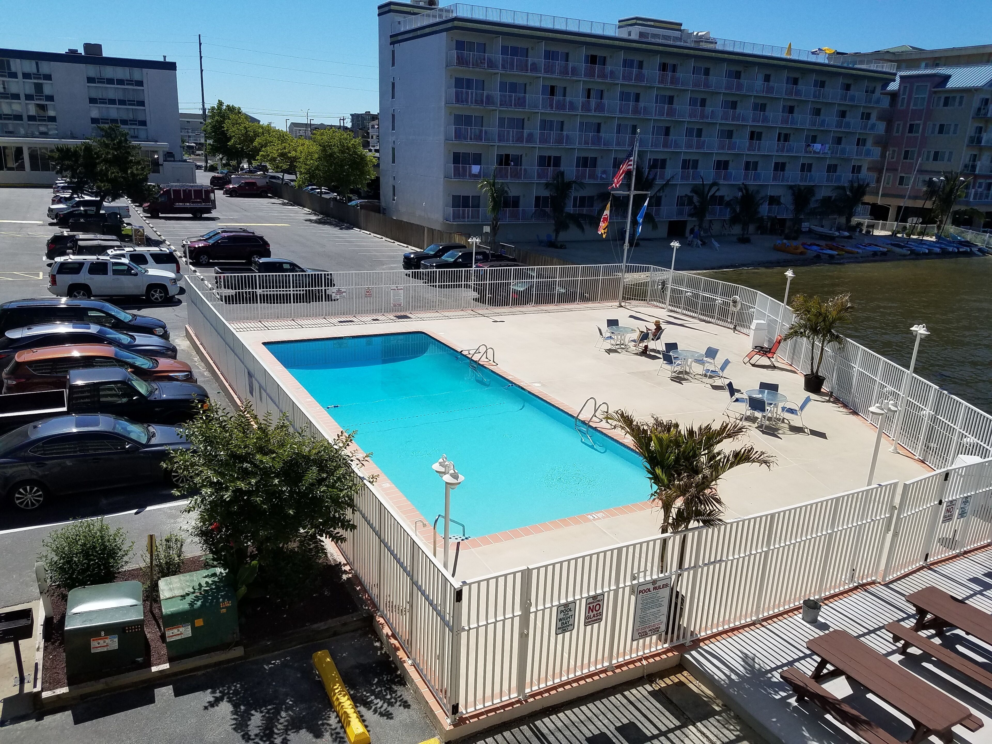 A swimming pool with a fenced deck, lounge chairs, and a view of the water.