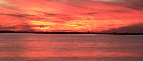 A sunset over a calm body of water with a silhouette of a distant landmass.