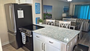Una cucina compatta con frigorifero, fornello e zona pranzo con tavolo e sedie.