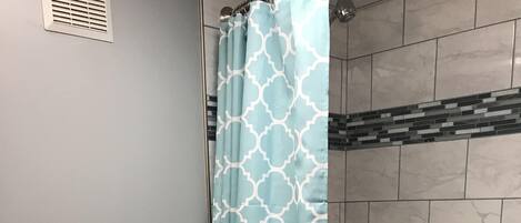 Ein Badezimmer mit Toilette, Duschvorhang, Badewanne und Mülleimer.