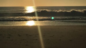 Una spiaggia con onde e il sole che tramonta o sorge.