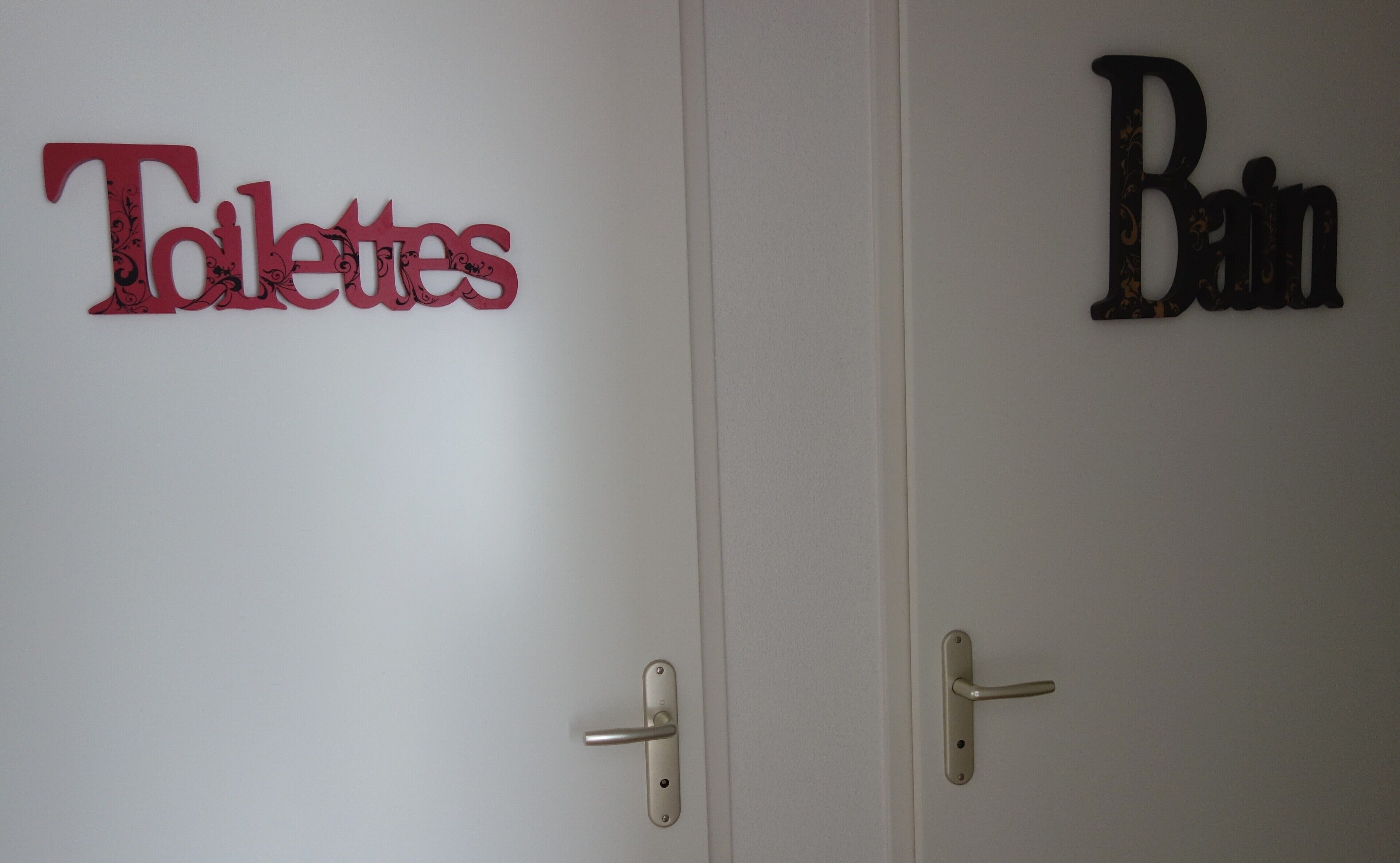 Deux portes avec les panneaux suivants : « Toilettes » et « Salle de bain ».