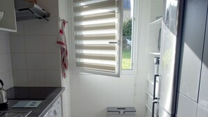 Eine kleine Küche mit Waschmaschine, Mülleimer und Kühlschrank.
