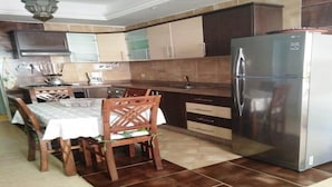 A modern kitchen with a refrigerator, wooden dining table, and chairs. - Beautiful apartment in Essaouira 4266 (Essaouira)