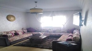 A living room with a sectional sofa, a coffee table, and a television. - Beautiful apartment in Essaouira 4266 (Essaouira)