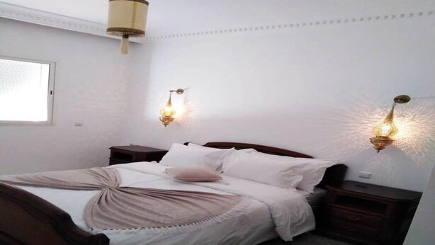 A bedroom with a bed, bedside tables, and wall-mounted lamps. - Beautiful apartment in Essaouira 4266 (Essaouira)