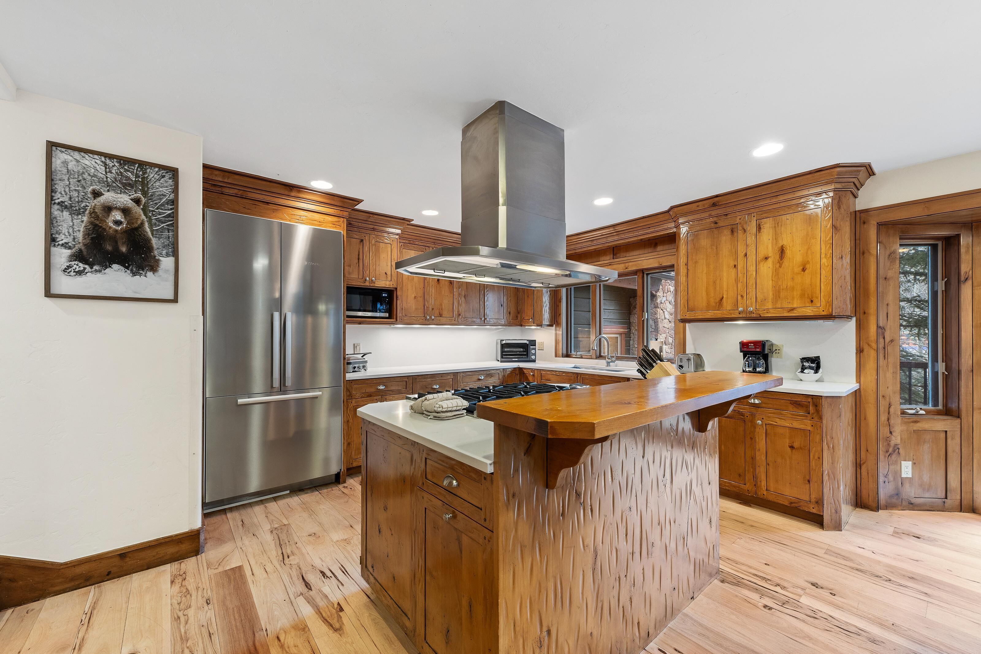 A modern kitchen with wooden cabinets, a stainless steel refrigerator, and a central island.