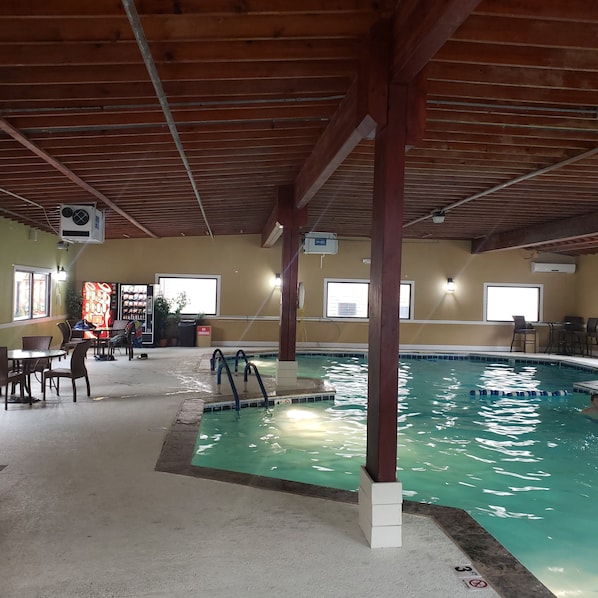 An indoor swimming pool with a wooden ceiling and a no smoking sign.