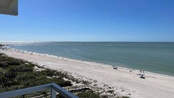 A beach view from a balcony with a clear sky.