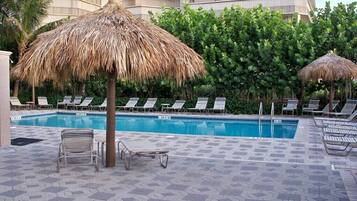 A pool area with lounge chairs and a thatched umbrella.