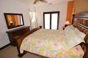 Un dormitorio con cama, cómoda, espejo, ventana con cortinas y ventilador de techo.