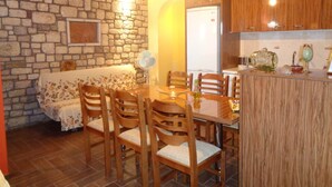 Uma sala de jantar com parede de pedra, teto de madeira e mesa de madeira com cadeiras.