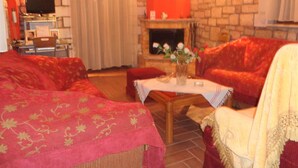 Uma sala de estar aconchegante com lareira, sofás vermelhos e uma televisão.