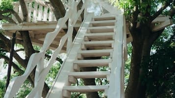 Ascend through lush foliage via a spiral staircase, blending seamlessly with the natural surroundings.