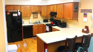 A kitchen with wooden cabinets, a black refrigerator, a stove, and a microwave. - Nordic Inn, Save 20% on Gorgeous 2BR, 2BA Condo! (Lincoln)