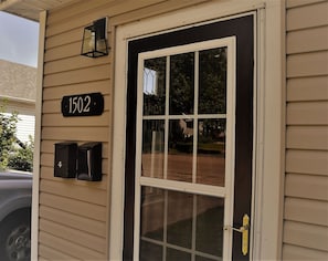 A beige house with a black door, a number '1502' sign, and two black mailboxes.
