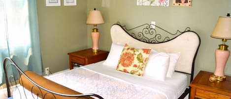 A neatly arranged bedroom with a bed, two bedside tables, a nightstand, and a blue chair.