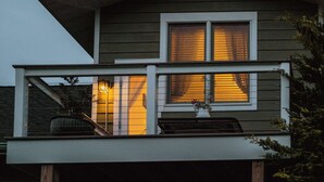 Ein zweistöckiges Haus mit Balkon, einem fenster mit Vorhängen und einer kleinen Veranda.