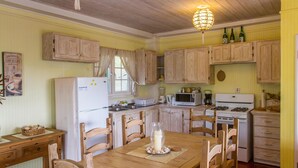 A kitchen with wooden cabinets, a refrigerator, a stove, and a dining table with chairs.