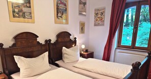 A bedroom with two beds, wooden headboards, and a window with curtains.