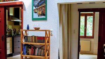 Ein Zimmer mit Bücherregal, einem Poster an der Wand und einem Fenster mit Blick auf Grünflächen.