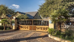 A gated entrance with a sign reading "ODE WERF" and a building with a sloped roof in the background. - Kuruman Hotel (Kuruman)