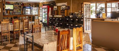 A restaurant with a checkered floor, wooden chairs, a bar area with a TV, and wine racks.