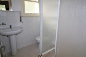 Un baño con un lavamanos blanco, un inodoro y una cabina de ducha de vidrio.