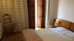 Ein Schlafzimmer mit einem hölzernen Bett, einem Nachttisch aus Holz, einem Stuhl und einem Holzschrank.