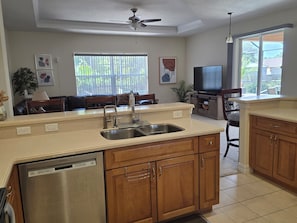 A kitchen with a dishwasher, wooden cabinets, a sink, and a ceiling fan.