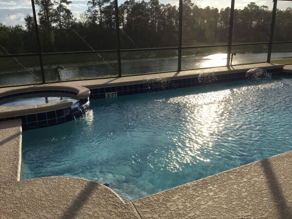 A swimming pool with a hot tub, surrounded by a fence and trees. - Waterfront-HUGE Pool-2.7 miles to Disney, w/ 4 Masters Suites, Arcades, Theater! (Kissimmee)
