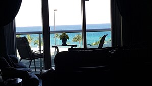 Una stanza con una grande finestra vista sull'oceano, un divano, una poltrona e un tavolino con una pianta in vaso.