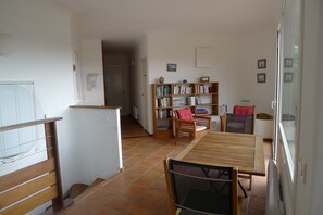Un vaste espace de vie comprenant une table à manger en bois, une bibliothèque et un coin cuisine.