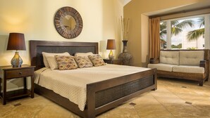 A bedroom with a large bed, two nightstands, a mirror, a sofa, and a window with a view of palm trees. - OCEANDREAM  Unit C 3bd/3bth (Cabarete)