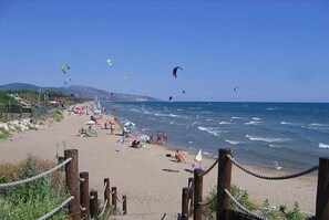 A beach with a wooden walkway leading to the shore, people relaxing on the sand, and several kites flying in the sky. - Villa Barbie  400 mt from beach (Sperlonga)