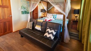 Un dormitorio con una cama con dosel, un sofá y una mesita de noche con lámparas.