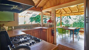 Una cocina con alacenas de madera, estufa a gas y una zona de comedor con sillas y una mesa.