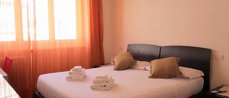 A neatly made bed with folded towels, a dark headboard, and two pillows.