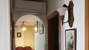 A hallway with an air conditioning unit, a ceiling fan, a framed picture, and a wall-mounted light fixture. - Quiet house, Garden, Huge beach 100m, Fishing (sea, river, boat) / Riomar (Deltebre)