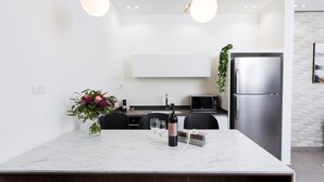 Eine moderne Küche mit Marmorarbeitsplatte, einem Edelstahlkühlschrank und einem Essbereich mit Stühlen und einem Blumenstrauß.