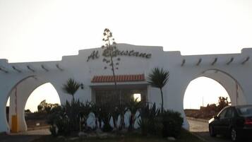 Un bâtiment blanc avec l’enseigne « Al Bustan » et deux arcades.
