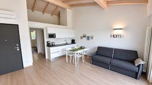 Ein modernes Apartment mit Küche, Essbereich und einem grauen Sofa.
