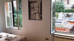 A room with a bed, a window with a view of a cityscape, and a painting on the wall. - Rome-Trastevere. Ideally located. All within walking distance. Internet (Rome)