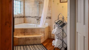 Een bad/douchecombinatie, een bubbelbad, een haardroger, handdoeken