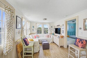 A cozy room with a sofa, a small table, a chair, and a TV.
