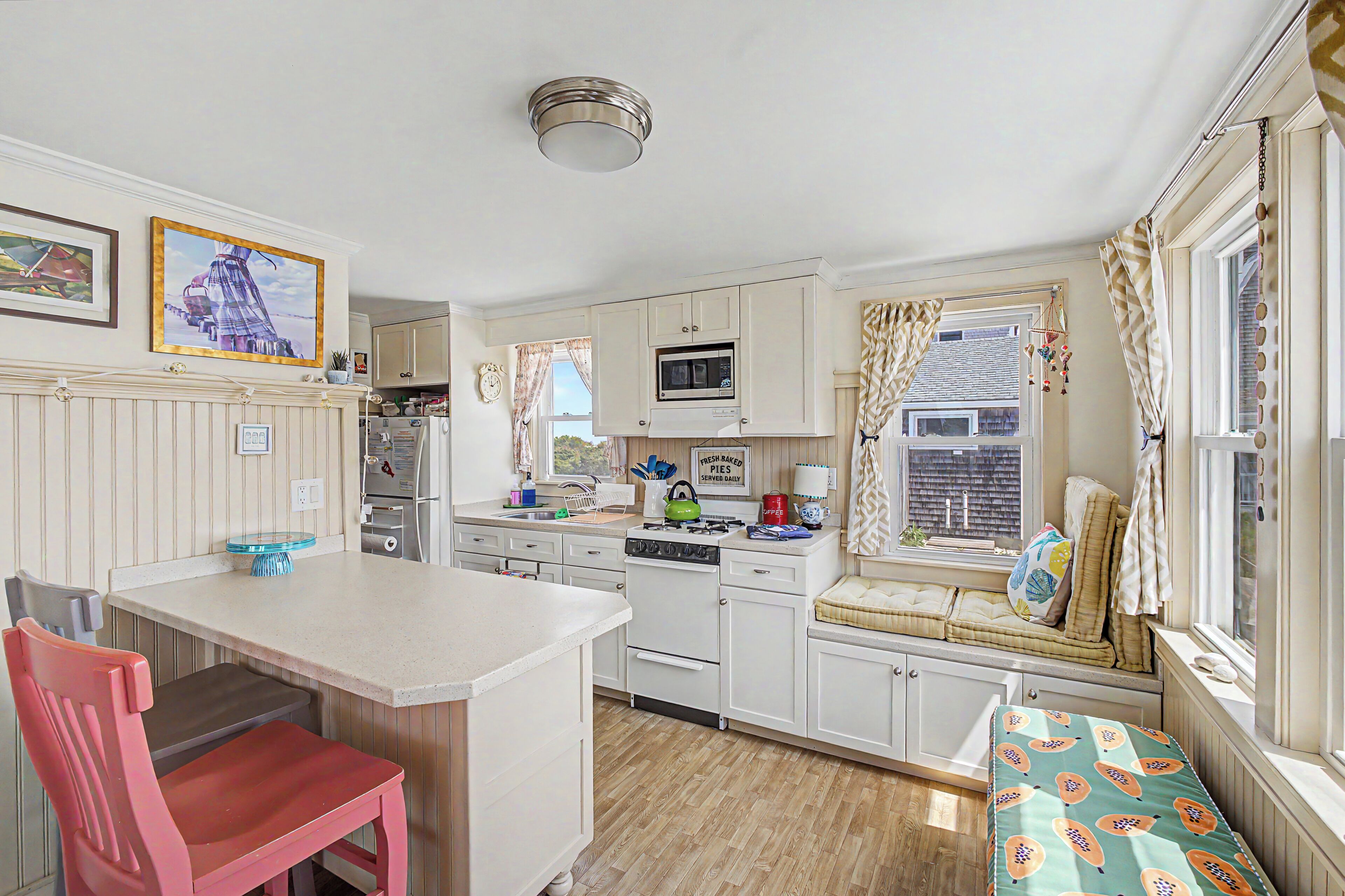 A compact kitchen with a dining area, a built-in bench, and a window with curtains.