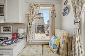 A kitchen with a window, a sign reading 'FRESH BAKED PIES SERVED DAILY,' a microwave, and a red coffee can.